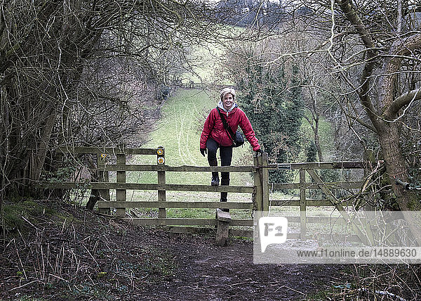 UK  Gloucester  Chipping Sodbury  Cotswold Way  woman on a hiking trip crossing pasture fence