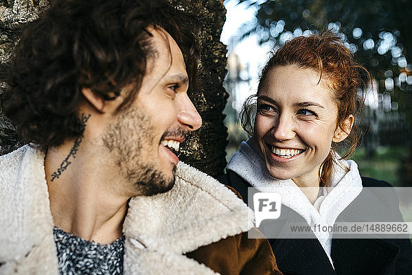 Portrait of happy couple at a tree trunk in park
