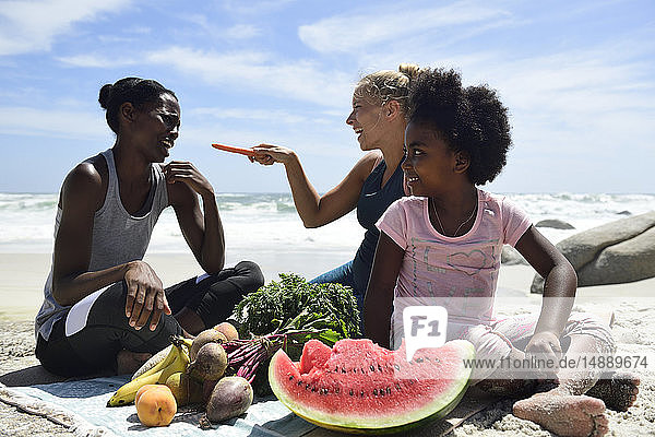 Mutter mit Tochter und Freundin beim Picknick am Strand