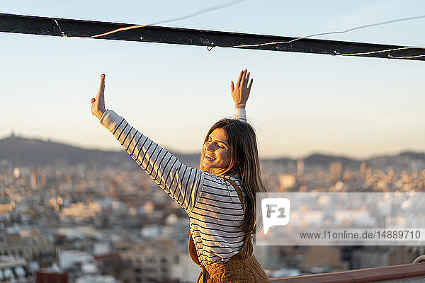Porträt einer glücklichen jungen Frau  die sich bei Sonnenuntergang auf der Dachterrasse entspannt
