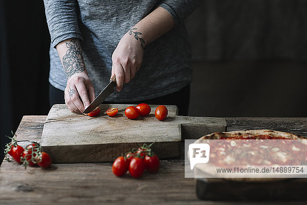 Junge Frau bereitet Pizza zu  schneidet Tomaten auf dem Schneidebrett