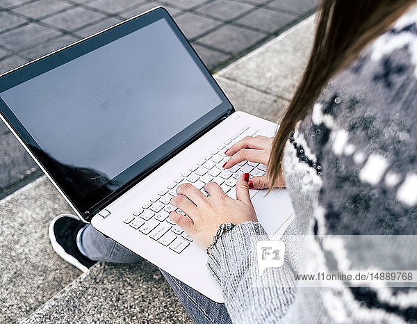 Nahaufnahme einer Frau  die mit einem Laptop im Freien auf einer Treppe sitzt