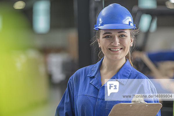 Porträt einer lächelnden Frau mit Schutzhelm in einer Fabrik
