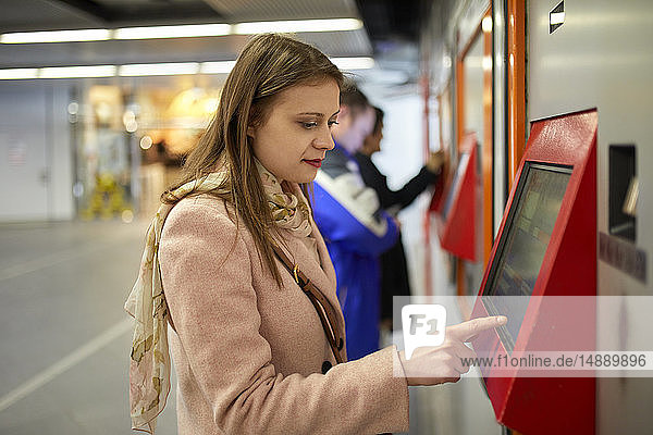 Austria  Vienna  young woman buying ticket from automated machine at station