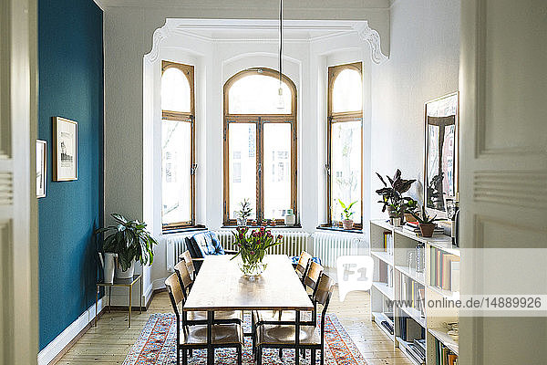 Holztisch und Stühle in modernem Wohnzimmer mit großer Fensterfront in stilvoller Wohnung
