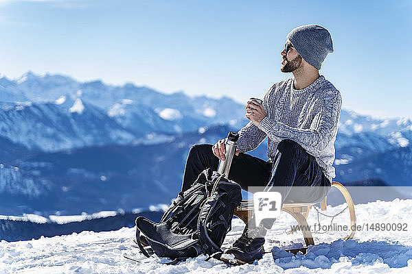 Deutschland  Bayern  Brauneck  Mann im Winter in den Bergen bei einer Pause