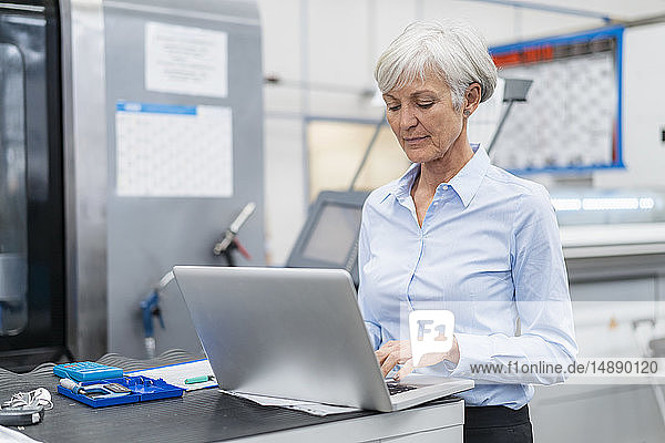 Senior businesswoman using laptop in a factory