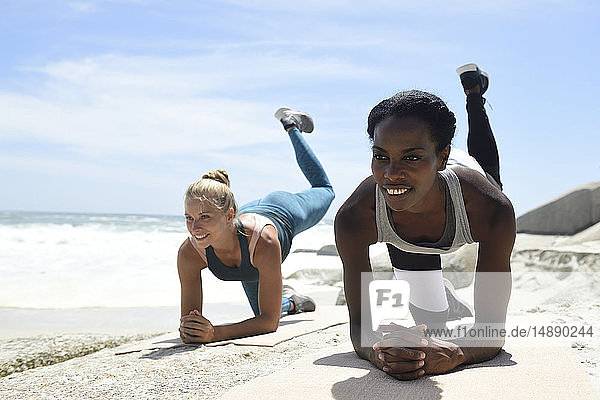 Two women doing a fitness exercise on the beach