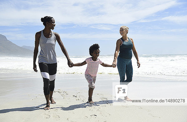 Happy mother with daughter and friend walking on the beach