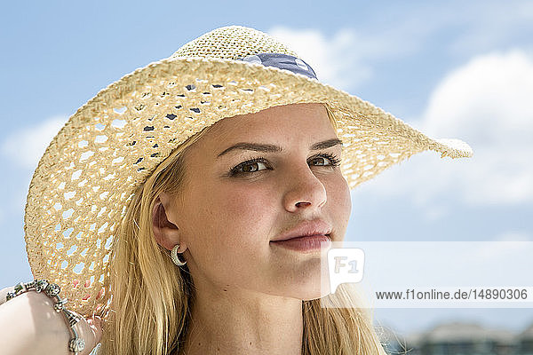 Porträt einer jungen Frau mit Strohhut am Strand