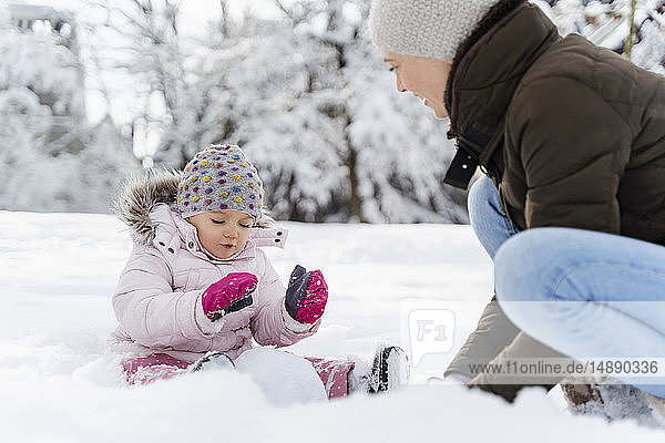 Happy mother playing with daughter in winter landscape