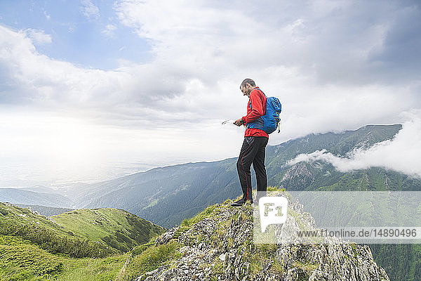 Mann steht auf einem Hügel und schaut auf seine Karte in den Karpaten  Rumänien