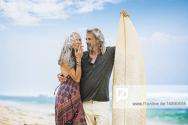 Älteres Hippie-Paar mit Surfbrett am Strand