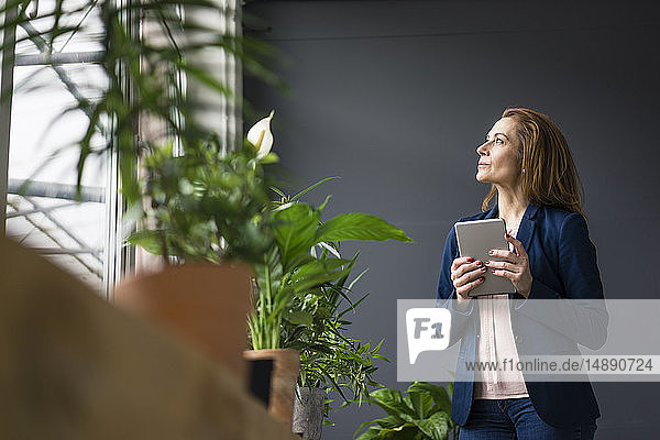 Reife Geschäftsfrau  die in einem nachhaltigen Büro arbeitet und ein digitales Tablet verwendet
