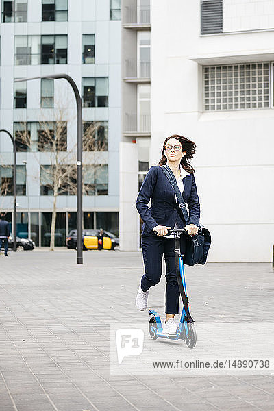 Aktive Geschäftsfrau auf dem Roller in der Stadt