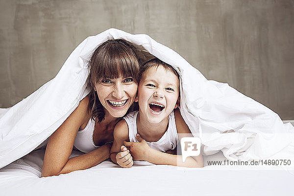 Mutter und Sohn kuscheln unter einer Decke  lachend