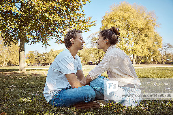 Junges Paar sitzt auf einer Wiese in einem Park