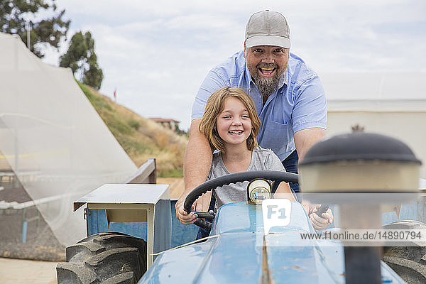 Landwirt zeigt seiner Tochter  wie man einen Traktor fährt