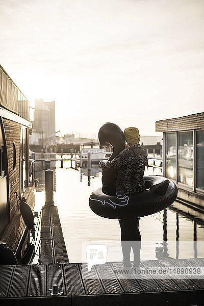 Geschäftsfrau mit schwimmendem Schwan steht auf einem Hausboot und schaut in die Ferne