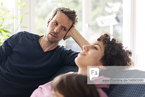 Mann beobachtet seine Frau beim Entspannen auf der Couch
