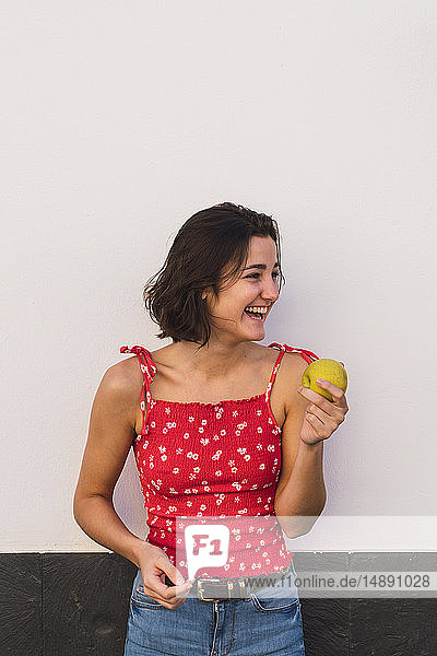 Lachende junge Frau mit Apfel
