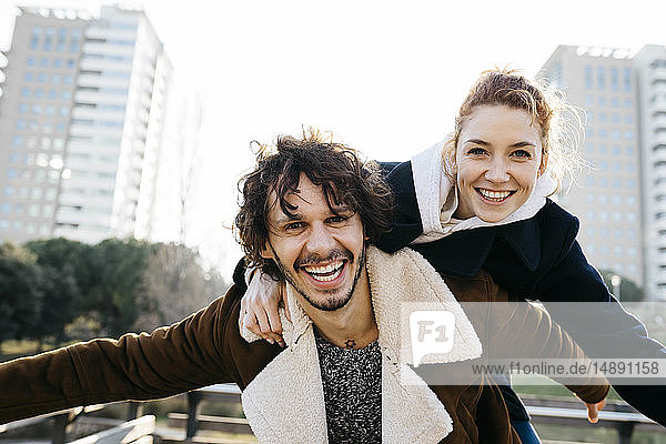 Happy couple enjoying piggyback ride in the city
