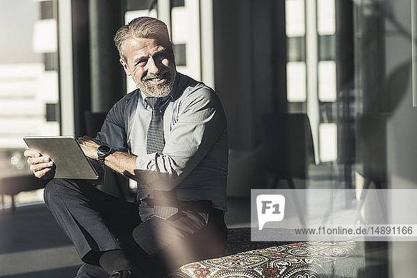 Smiling mature businessman using tablet in office
