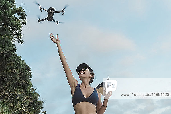 Indonesien  Bali  Nusa Dua  Frau fliegende Drohne am Strand