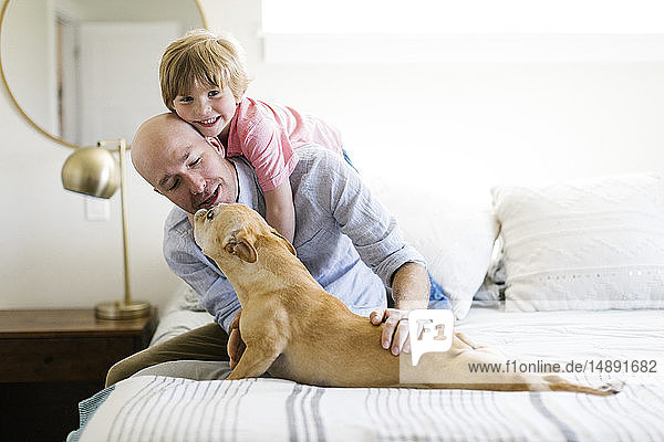 Vater und Sohn auf dem Bett mit ihrem Hund