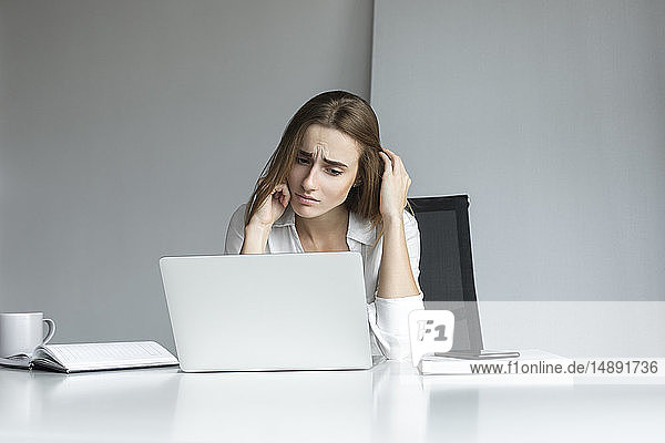 Frustrierte Geschäftsfrau bei der Arbeit am Laptop