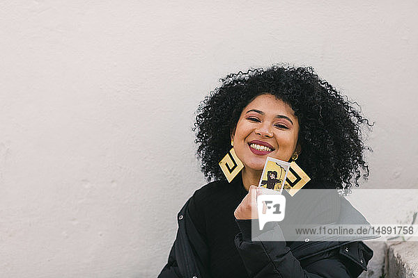 Lächelnde junge Frau mit einem Foto von sich selbst