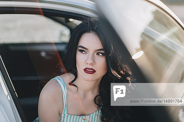 Junge Frau mit rotem Lippenstift im Auto sitzend