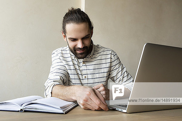 Young businessman putting USB stick into laptop