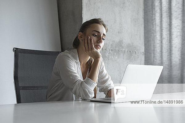 Gelangweilte Geschäftsfrau bei der Arbeit am Laptop