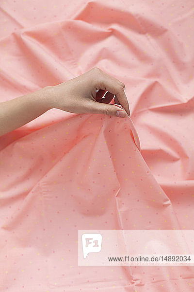 Hand einer Frau hält rosa Stoff