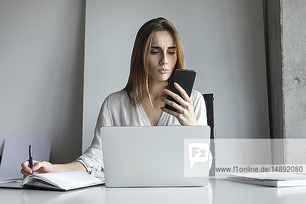 Young businesswoman looking at smartphone
