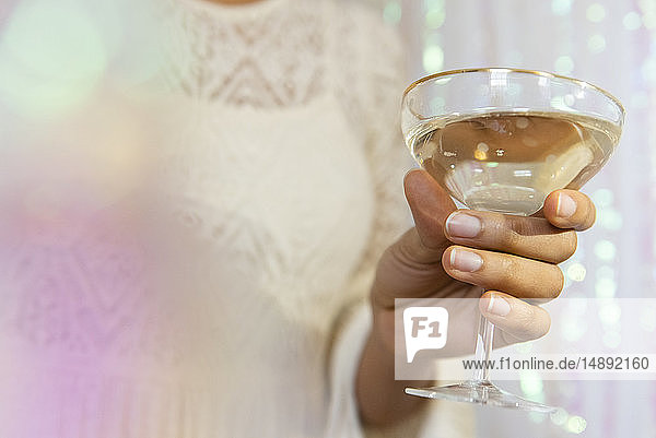 Die Hand einer jungen Frau hält ein Glas Weißwein