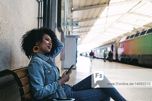 Junge Frau mit Smartphone auf dem Bahnsteig