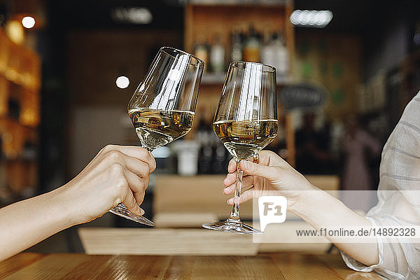 Hands of women toasting with glasses of white wine