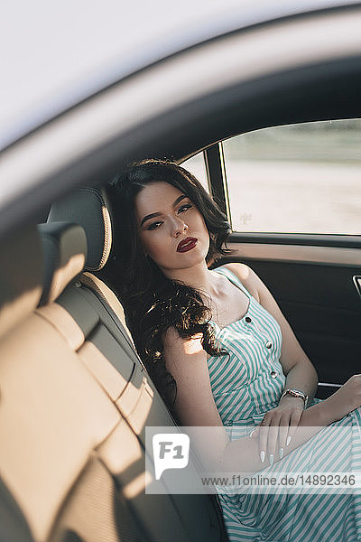 Junge Frau in gestreiftem Kleid sitzt im Auto