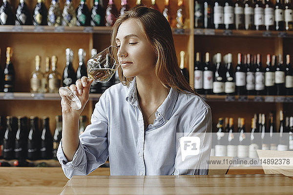 Junge Frau schnuppert an einem Glas Weißwein