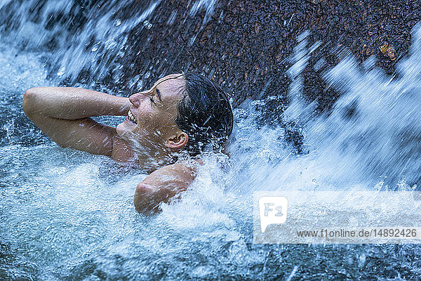 Frau mit geschlossenen Augen unter einem Wasserfall in Phuket  Thailand