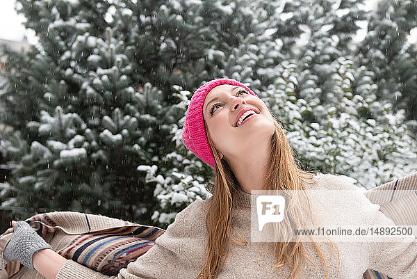 Junge Frau mit Wollmütze schaut in den Schnee