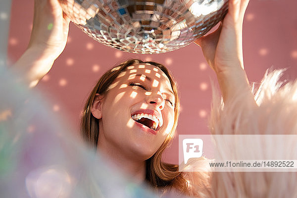 Smiling young woman holding mirror ball