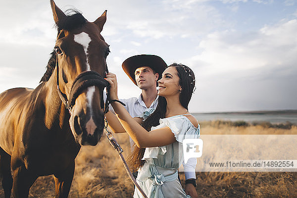 Junges Paar mit Pferd auf einem Feld