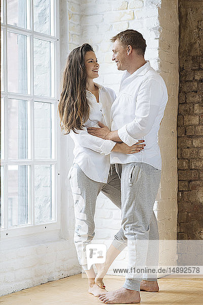 Smiling couple embracing by window