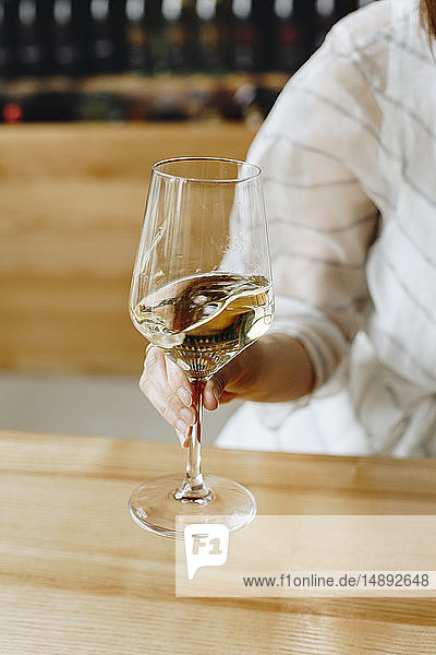 Hand einer Frau hält ein Glas Weißwein