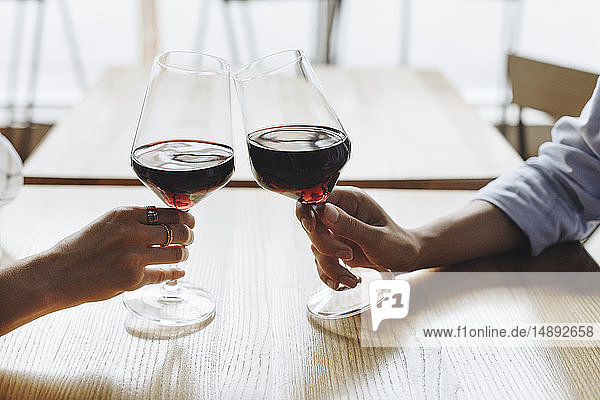 Hands of women toasting with glasses of red wine