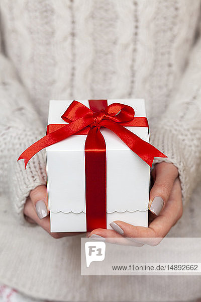 Hände einer Frau halten Weihnachtsgeschenk mit Zuckerstange