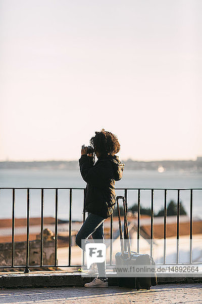 Junge Frau beim Fotografieren am Geländer